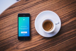 an iPhone showing Salesforce experts to follow on Twitter next to a cup of coffee